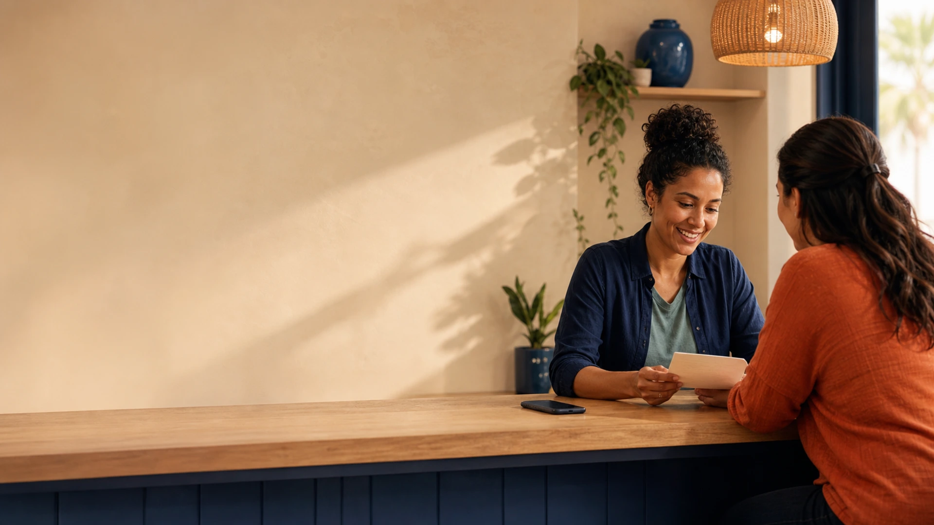 A diverse local business owner smiling while helping a client with a simple note at a warm service counter