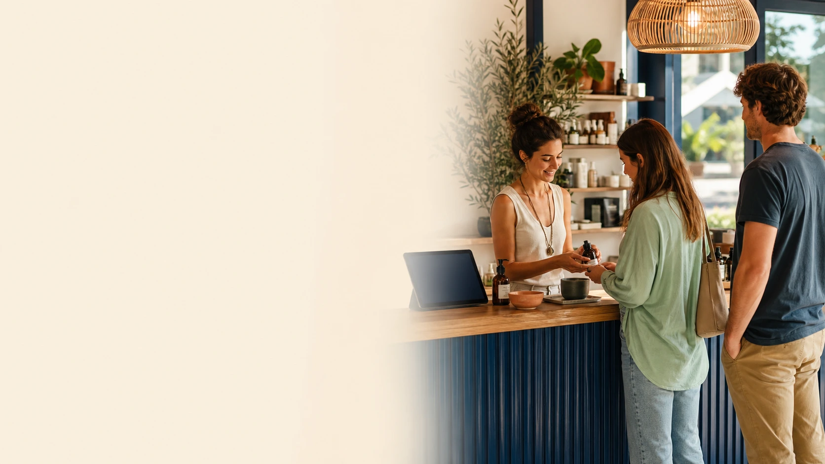 A local shop owner helping customers at the counter with a laptop off to the side
